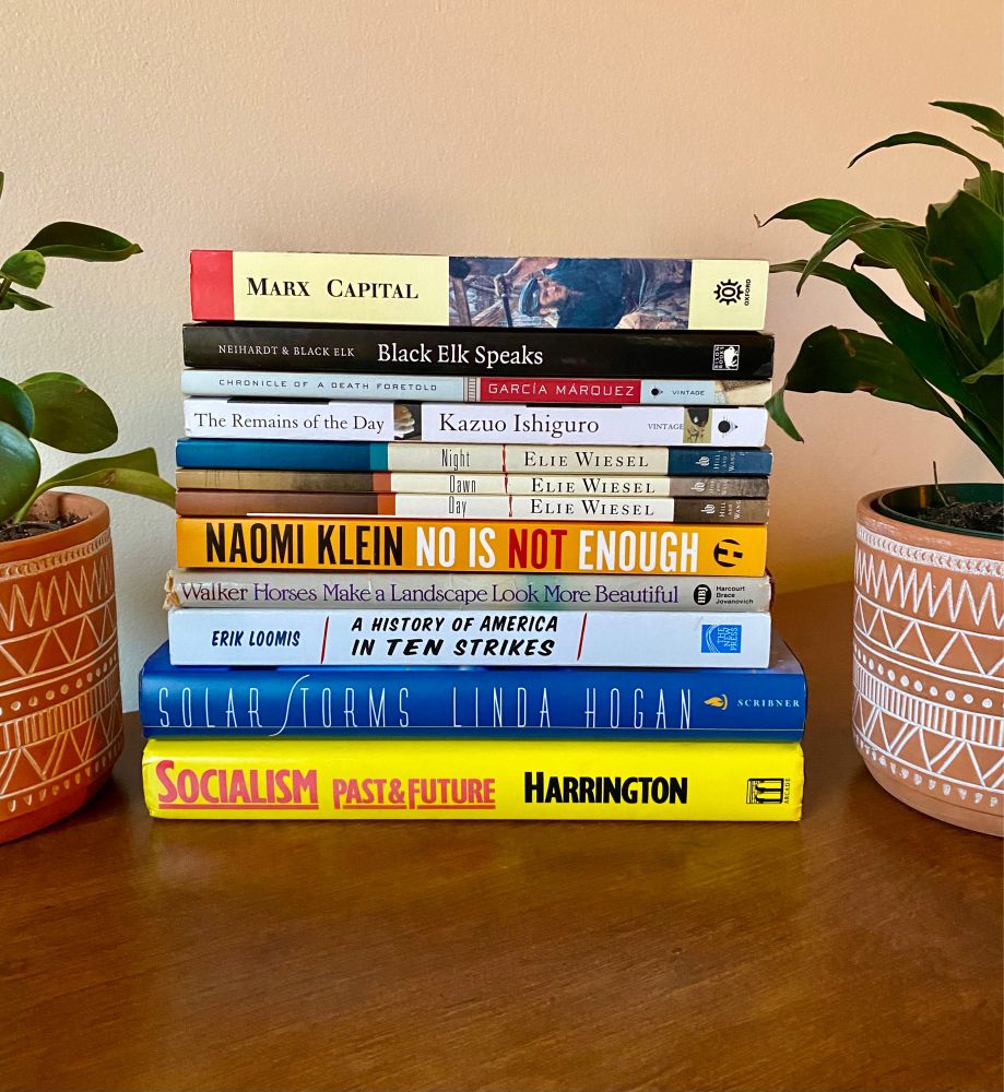 A photo of a stack of 12 books on a table.