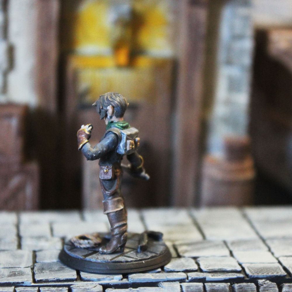 Back-side view of a painted miniature rogue. The back of her hair is cut short, but the voluminous top sweeps to the side. She has a variety of bags and pockets.