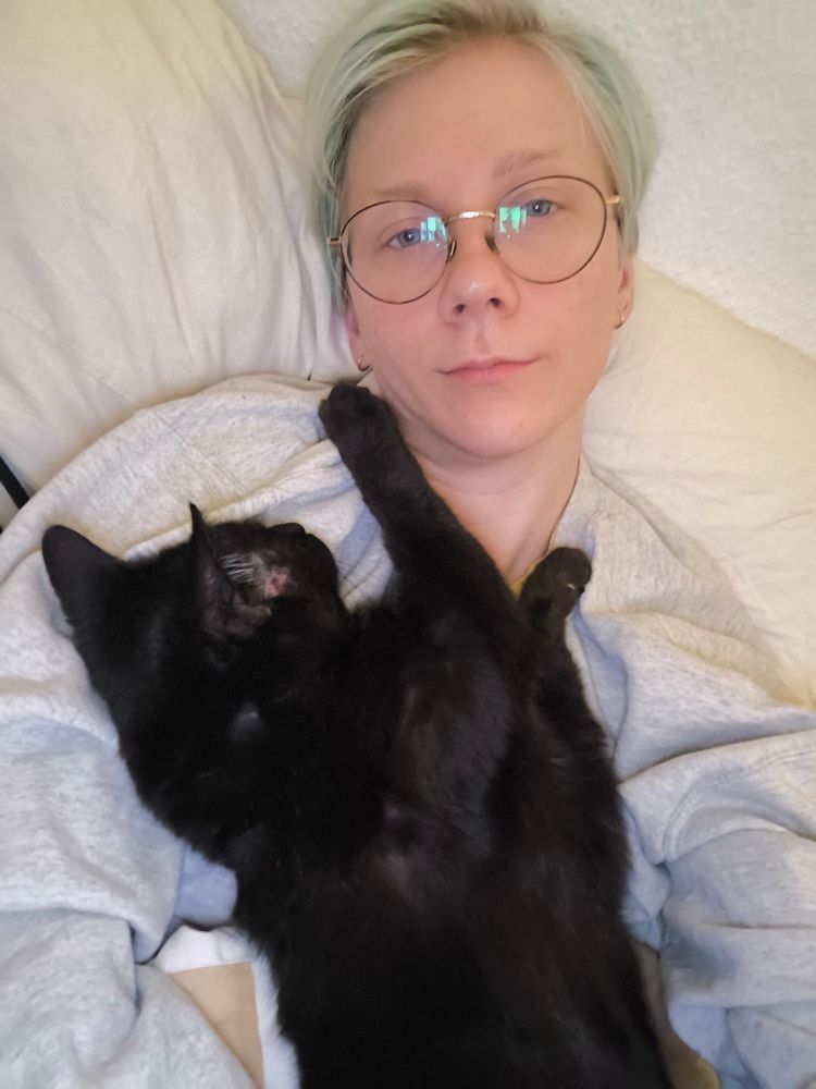 Phin with his black cat Linnea sleeping on his chest