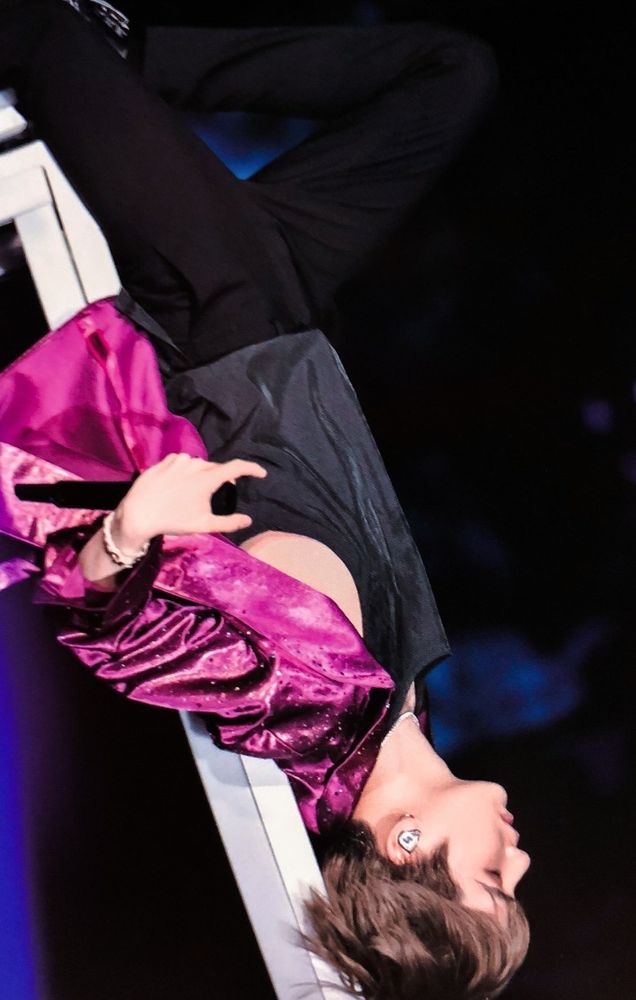 Yoongi está deitado em um banco durante uma apresentação de Seesaw. A maior parte de suas roupas são pretas, exceto pelo casaco pink que está escorregando dos ombros.

Yoongi is lying on a bench during a performance of Seesaw. Most of his clothes are black, except for the pink coat that is falling off his shoulders.