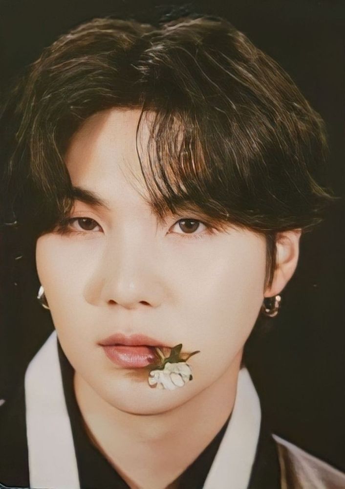 Yoongi está com uma expressão séria enquanto veste uma roupa tradicional coreana e está usando um par de brincos de argola prateados. Além disso, ele está segurando uma flor branca com a boca. A foto é do card solo do Yoongi para o photoshoot do BTS em comemoração ao Chuseok em 2022.

Yoongi has a serious expression while wearing a traditional Korean outfit and a pair of silver ring earrings. Additionally, he is holding a white flower in his mouth. The photo is from Yoongi's solo card for BTS's 2022 Chuseok photoshoot.