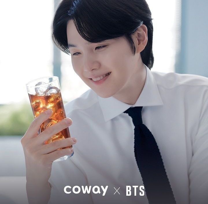 Yoongi aparece vestido de camisa social branca e gravata preta enquanto olha para um drink em sua mão e sorri. É a nova foto para merchandising dos produtos da Coway.

Yoongi is dressed in a white dress shirt and black tie while looking at a drink in his hand and smile. It is the new photo for merchandising Coway products.