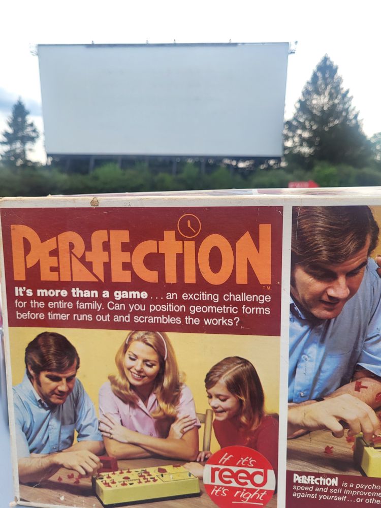 The game of Perfection, version 1973. A drive in screen and trees are in the background.