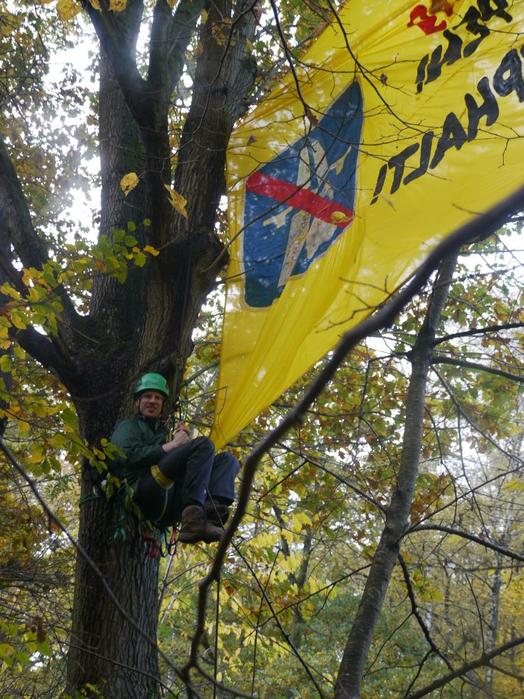 Mensch hängt in Seilen neben Banner, 1 Autobahn logo ist durchgestrichen