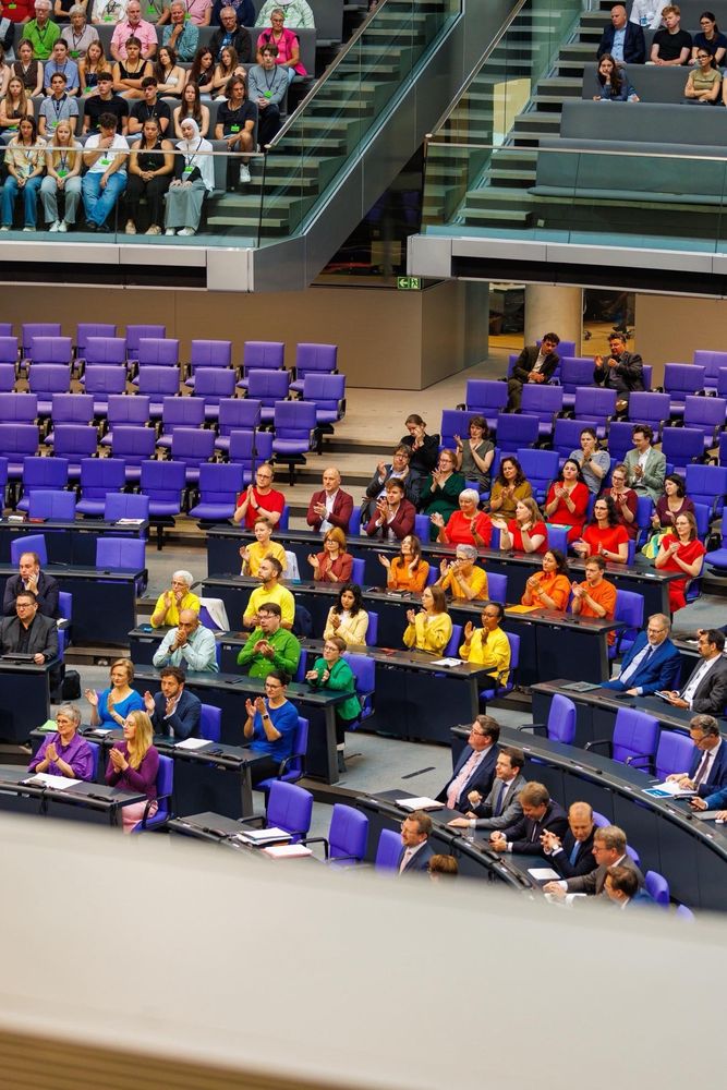 Man sieht ein Bild aus dem Bundestag. Die Grüne Fraktion ist gekleidet wie ein Regenbogen. 