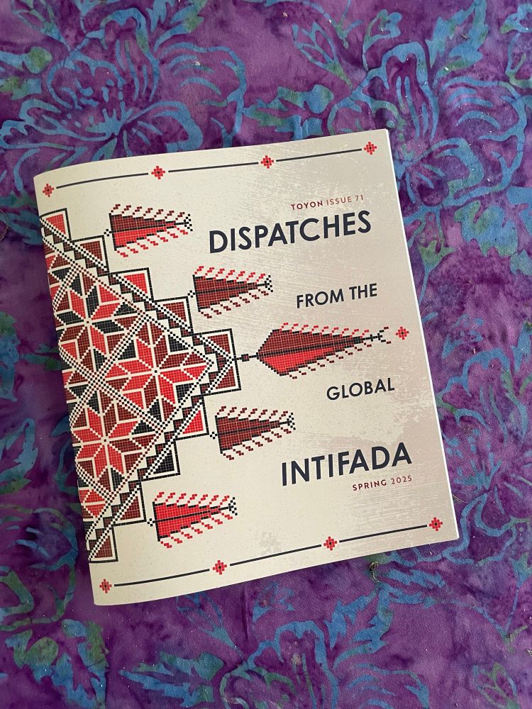 A beige, red, and black magazine cover reading “Dispatches from the Global Intifada.” It is lying on a purple and blue batik dyed cloth. 