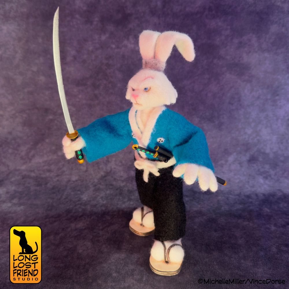 Completed Usagi Yojimbo needle felted figure, posed in a battle stance, brandishing a katana in his right hand