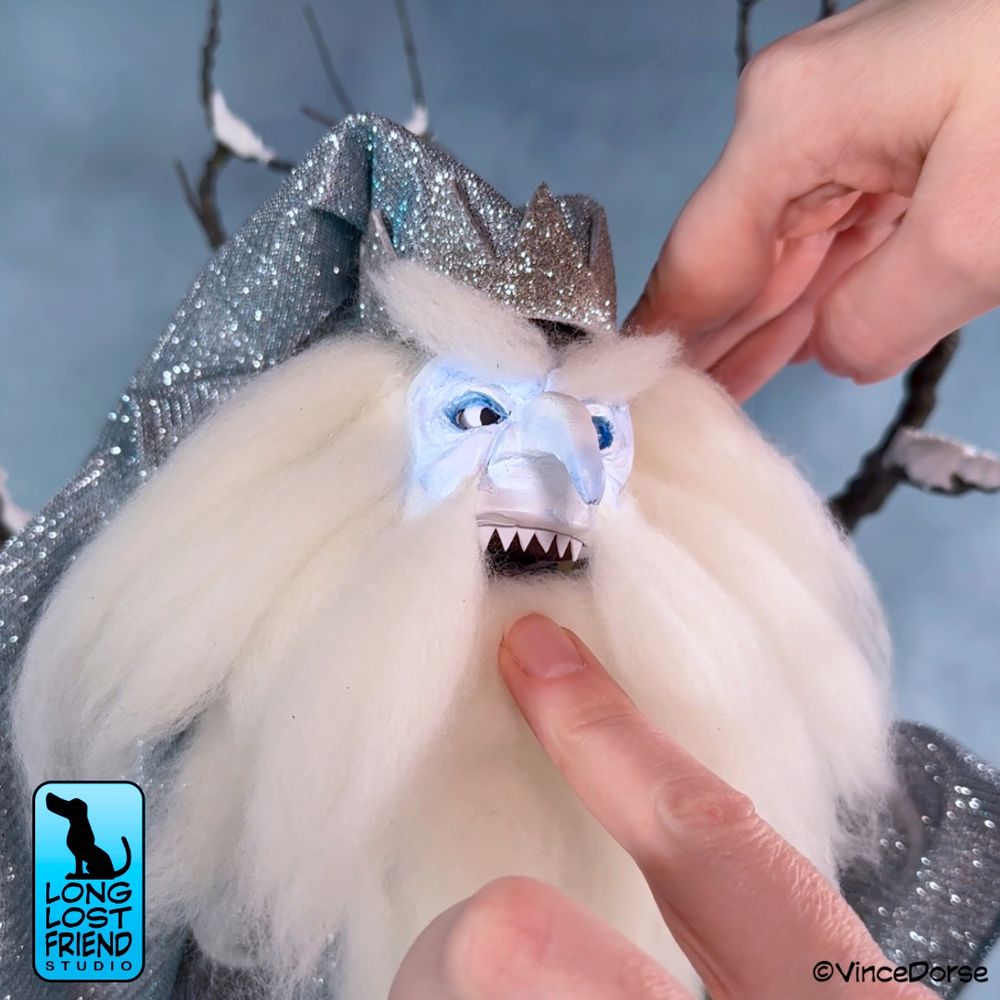 Our take on the Winter Warlock from Santa Claus Is Comin' to Town. An art doll with sculpted head and hands, and a glittery silver robe and hat. HIs jaw is hinged, so in the photo I'm adjusting his mouth to show more teeth.  Winter Warlock made by Vince Dorse.