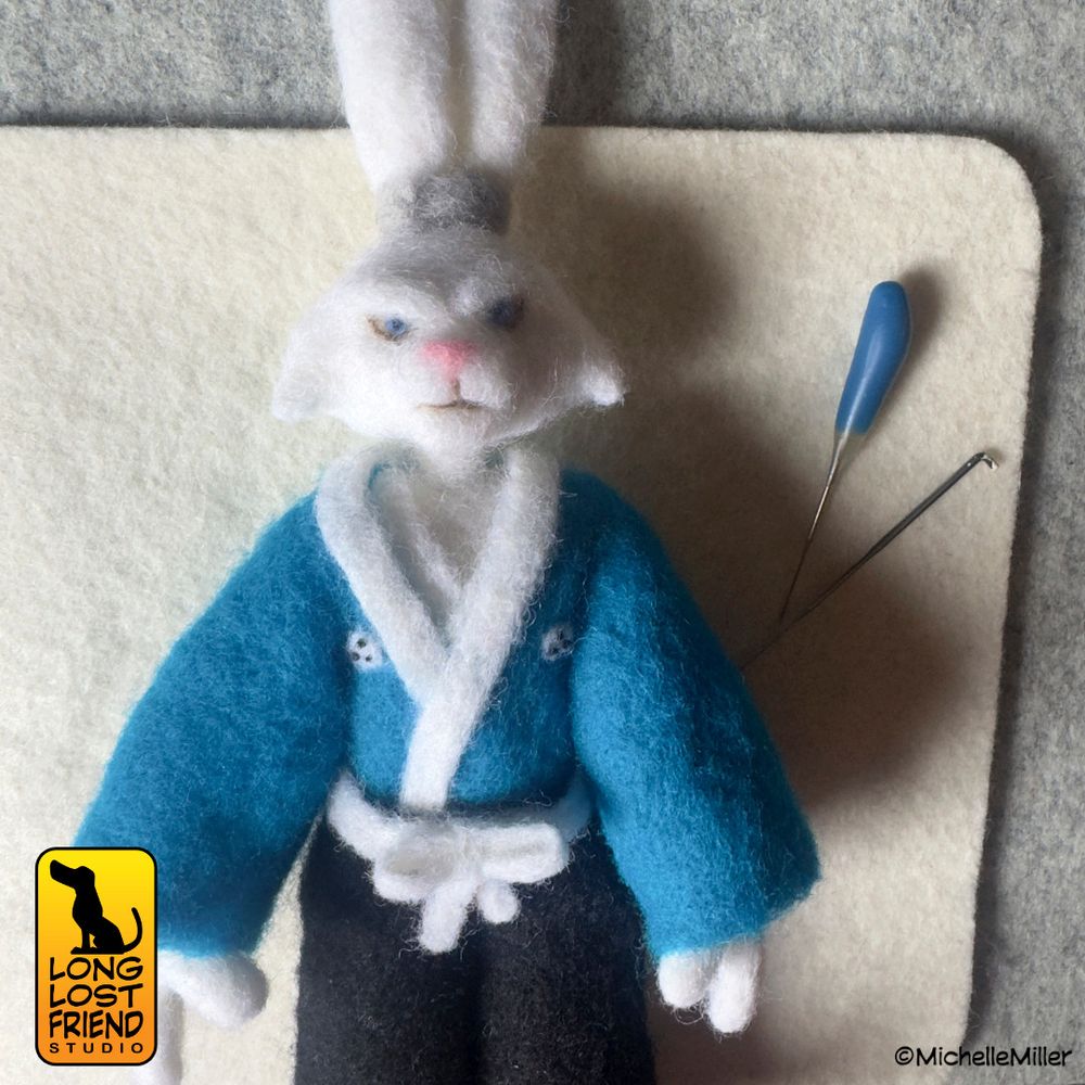 Usagi Yojimbo needle felted figure in progress, lying on the felting pad with felting needles nearby