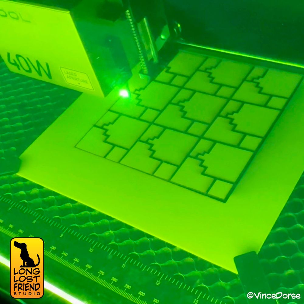 image of the Super Mario base inside the bed of a laser engraver, the design - based on the terrain in the video game - is being cut from wood by a laser