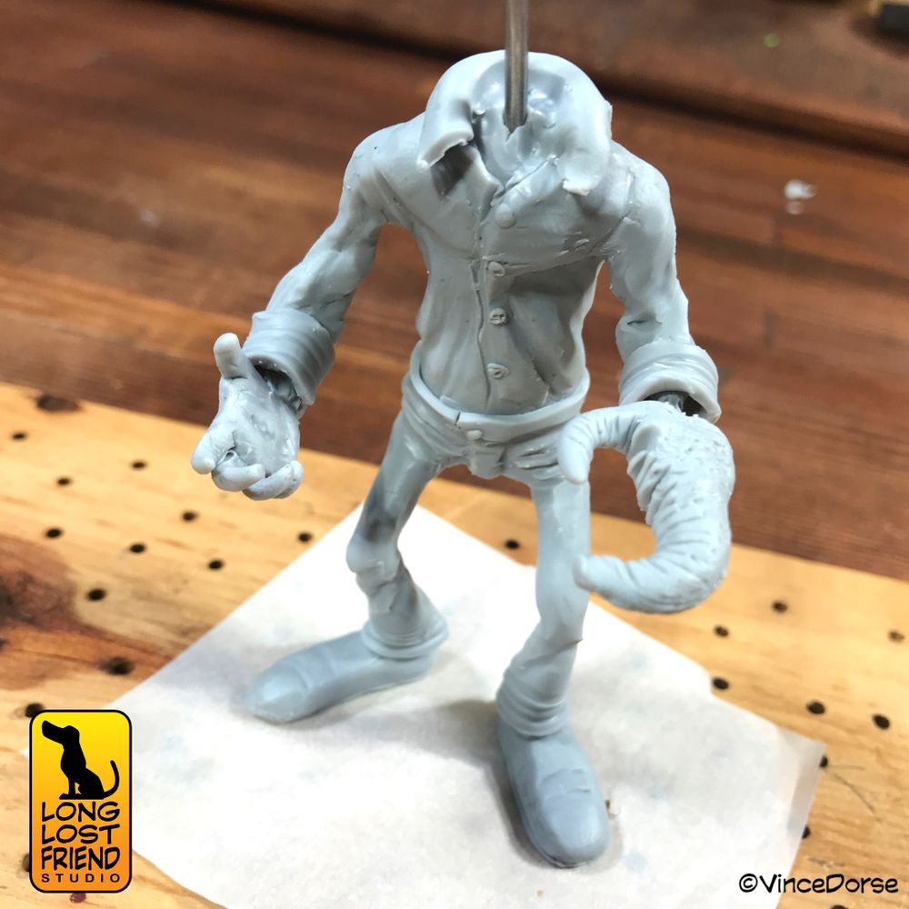 polymer clay sculpt in progress of a man with one human hand, and one giant fly claw