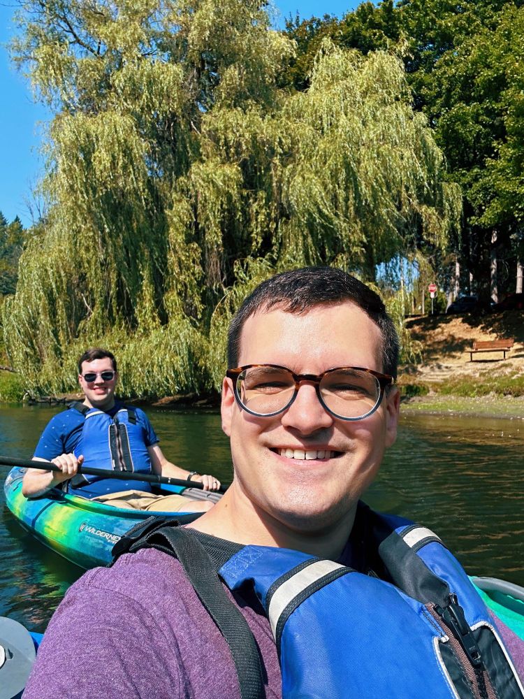 Selfie of Alex and I kayaking near the shore with a willow tree in the background