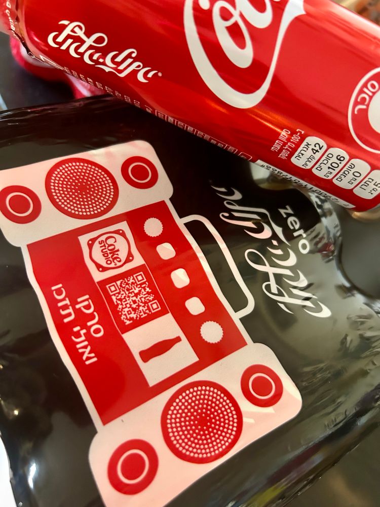 Ein Gebinde Cola-Zero Dosen und eine Cola-Classic Dose. Beschriftet auf Hebräisch. 