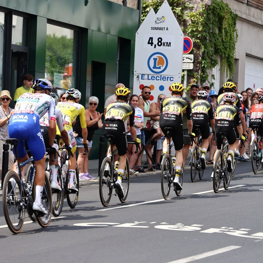 Plusieurs cyclistes devant le début de la côte de la Baraque.
Dont, Tadej Pogacar et Jonas Vingegaard.
Le panneau indiquant "Sommet à 4,8km sponsorisé par E.Leclerc.
Quelques personnes aplaudissant au passage des cyclistes.