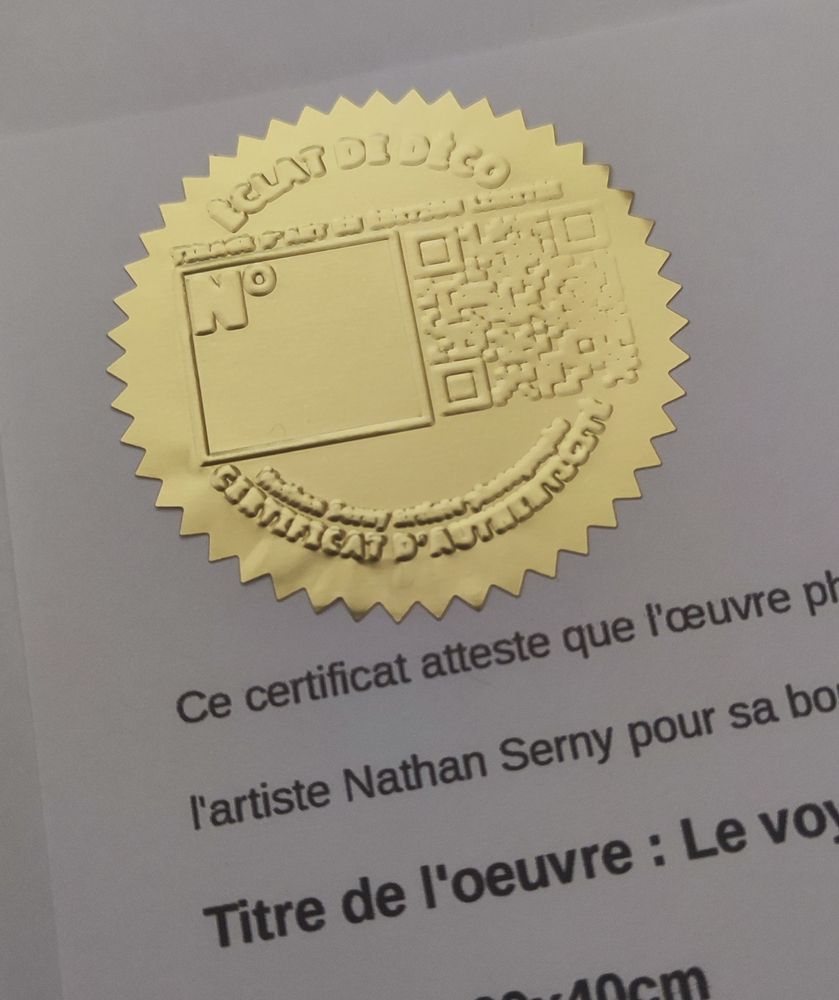 Présentation de mon nouveau certificat d'authenticité.
Gaufrage sur un autocollant couleur OR avec du texte incluant le titre de ma boutique, mon nom et prénom, la mention certificat d'authenticité, un QR code et enfin un espace pour signer.

En dessous on aperçoit une partie de la feuille A4 avec les détails sur l'œuvre vendue.