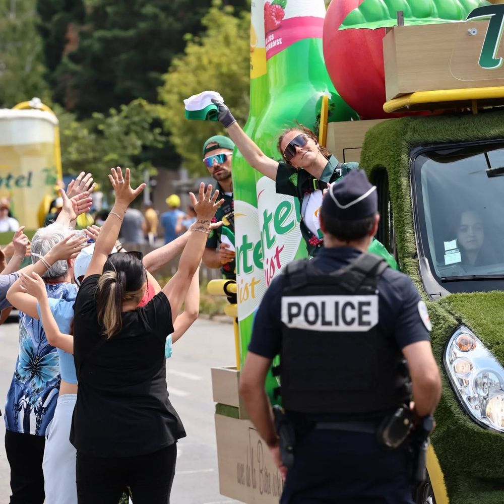 Un policier surveillant la caravane publicitaire du Tour de France 2025, au cas ou un pauvre voudrait voler une canette à 1,5€ pour survivre.