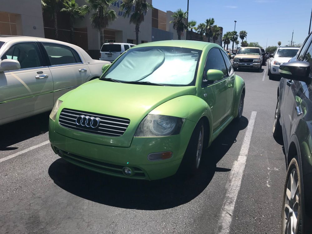 A lime green “BeeTTle” in a parking lot. 