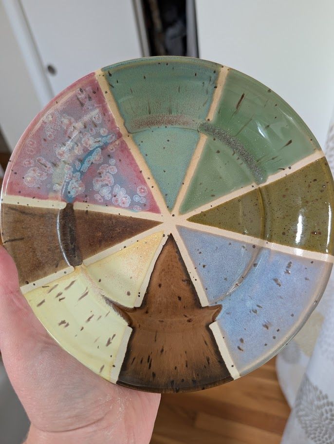 A circular plate, approx 8" diameter, divided into 8 wedges. Each wedge has a different glaze color.