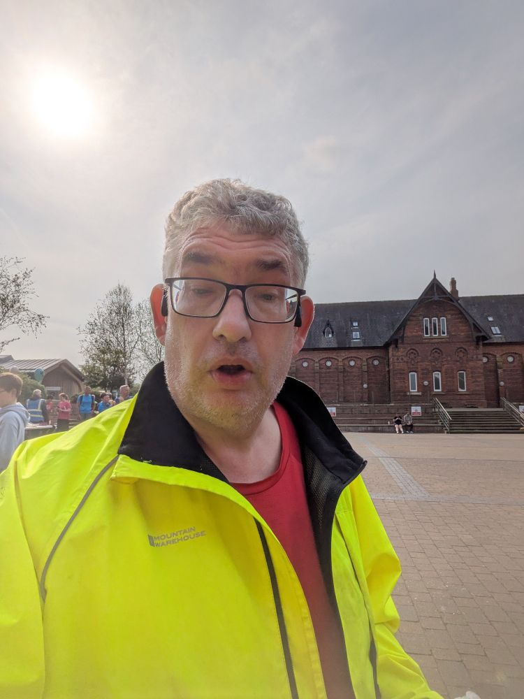 The unshaven post author in running jacket, with one of the buildings in Stewart Park behind him.
