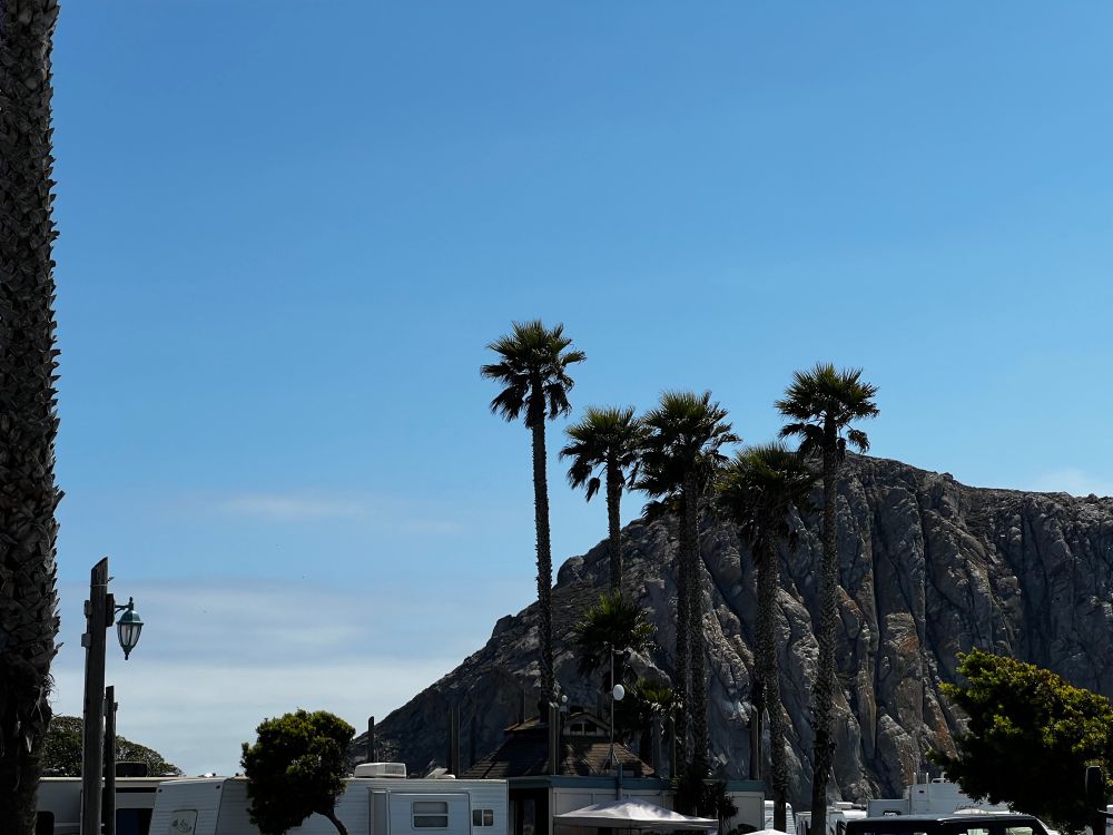 A photo of Morro Rock, towering over an RV park. It is an old volcano plug, a huge rock shooting up from the ocean.