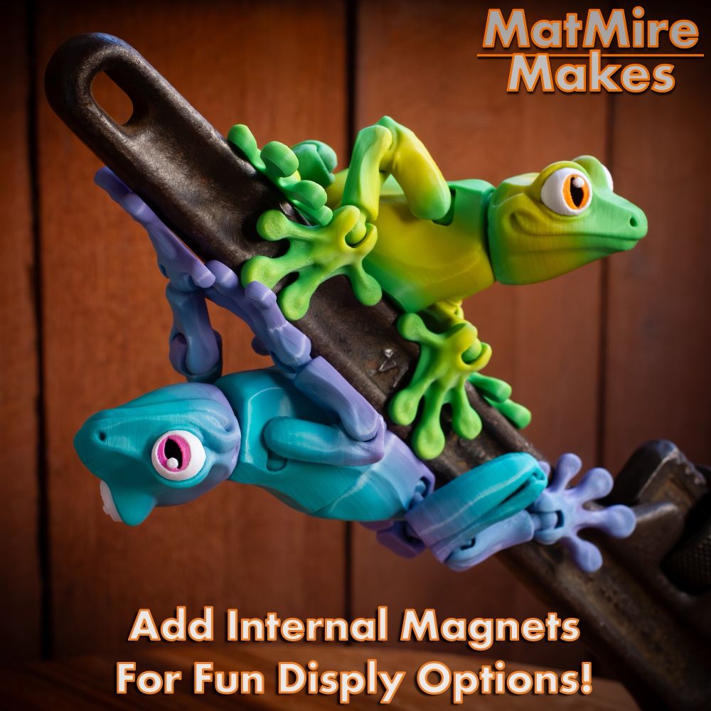 Green and purple-blue 3D printed frogs. Magnetically holding on to a metal handle.