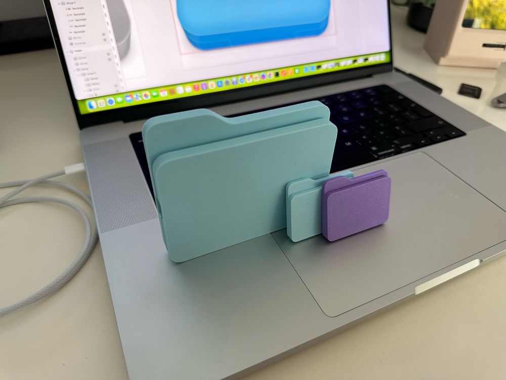 3D printed, blue Samsung SSD case in the shape of the macOS system folders. Photographed on the top of a MacBoom Pro keyboard.