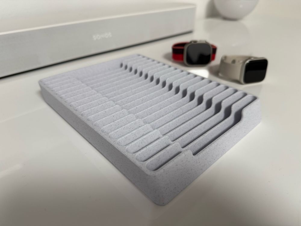 A close-up of an empty gray watch band organizer tray with clean, evenly spaced grooves designed to hold multiple watch straps. 