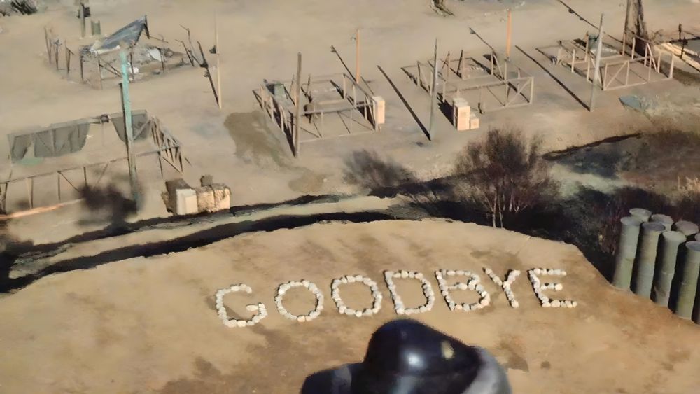 An aerial view of a dusty military camp features the word "GOODBYE" spelled out on the ground with white rocks. The sparse camp includes tents, empty wooden frames, and scattered equipment, evoking the final scene from the M*A*S*H series finale, "Goodbye, Farewell and Amen," originally aired in 1983.