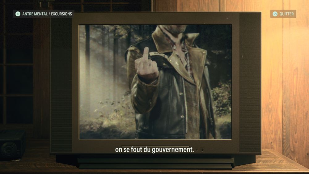 Screenshot du jeu Alan Wake 2 où on voit un mec dans une télé faite un doigt d'honneur et en sous titre
"on se fout du gouvernement"