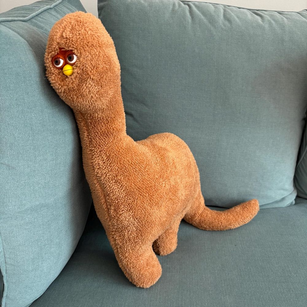 it is what it says in the skeet. i do not know how else to describe it. it is sitting in the corner of a light gray-green-blue couch that makes me feel color blind and the dino nugget long furby is dino shaped and dino nugget colored (brown). it has a dino tail and a furby face and is a plushy. idk i want it, should i get it?
