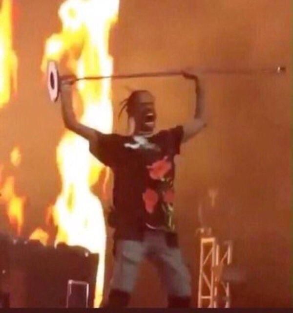 travis scott holding up microphone stand in front of fire meme