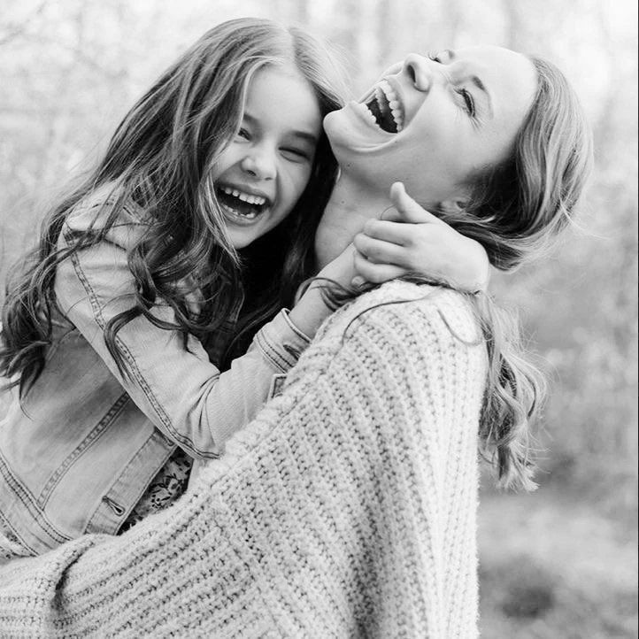 Mother holding her daughter; both are smiling