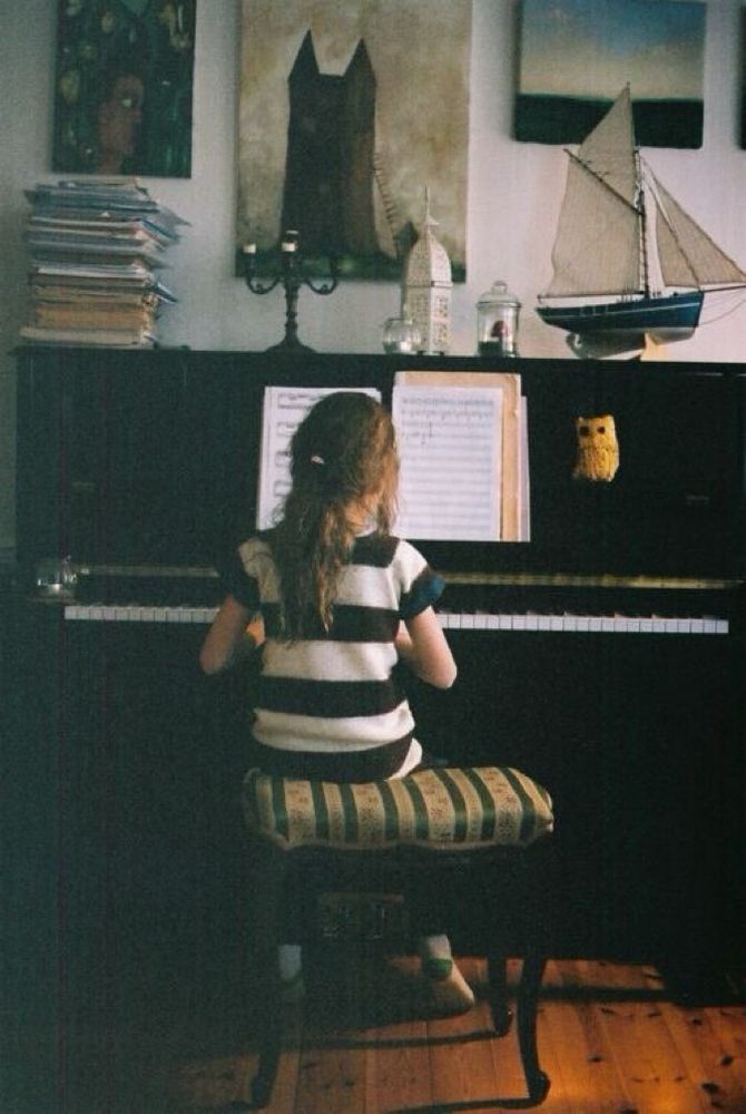 A young girl sitting at a piano.