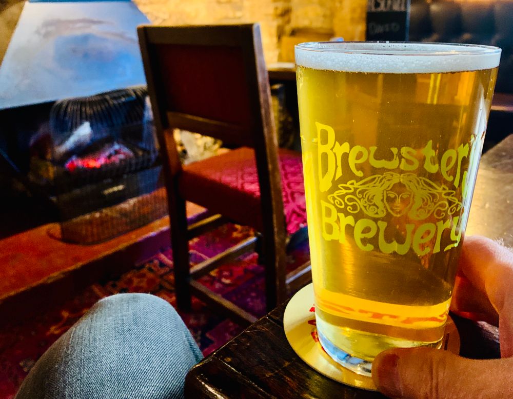Pint of pale beer in a Brewsters Brewery glass in front of the fire.