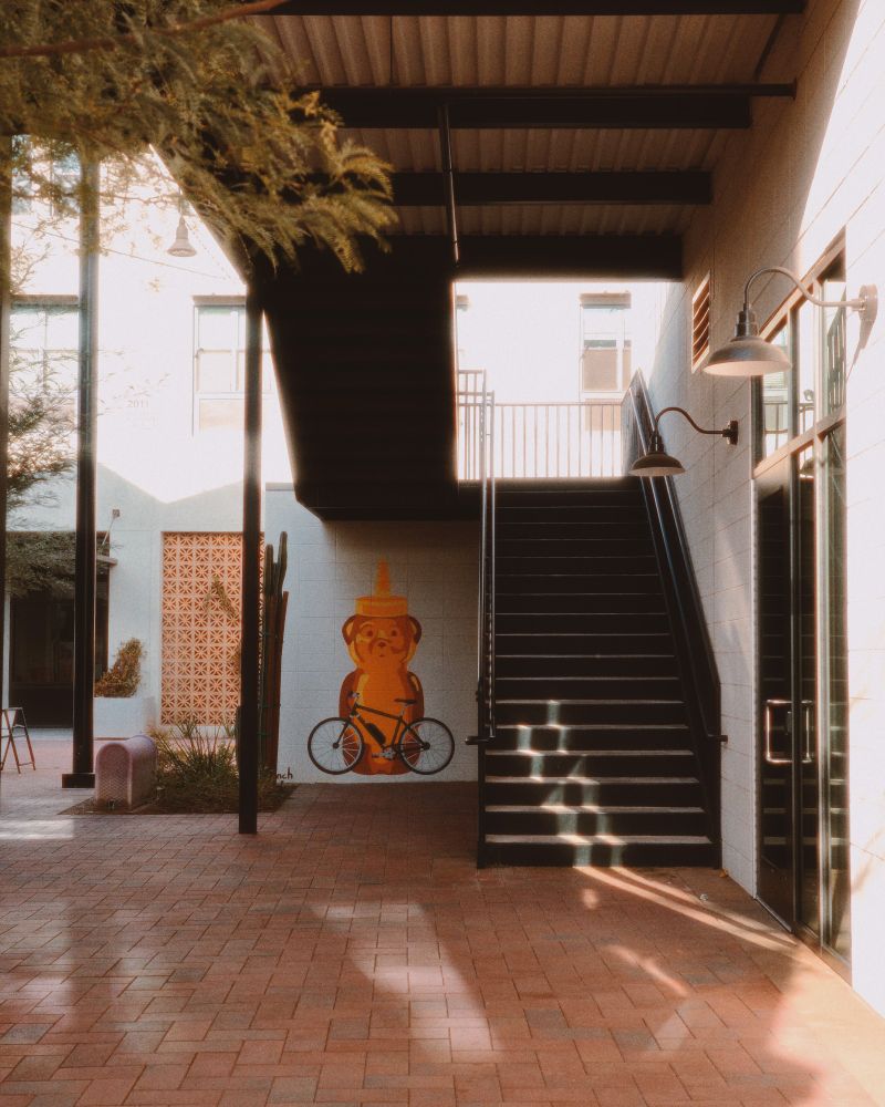 photo of an outdoor hallway of an apartment complex, with a notable honey bear bottle art graphic mural by a staircase