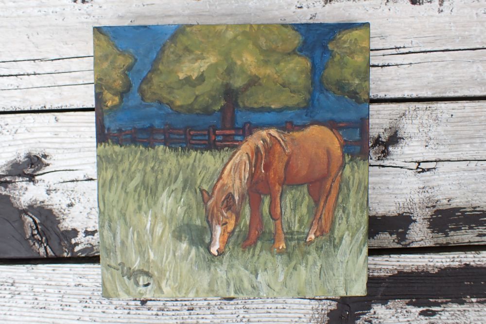 A chestnut pony grazing in a fenced off field. Egg tempera on wood panel. 6x6"