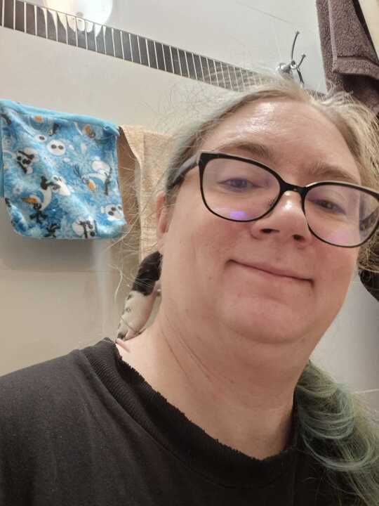 Potato enby smiling to the best of their ability, they have an itty bitty 16 day old baby rat on their shoulder.