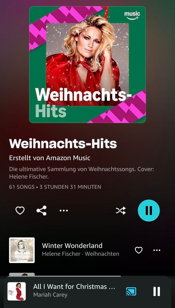 Screenshot von Amazon Music: Playlist-Cover ‚Weihnachts-Hits‘ mit Helene Fischer in rotem Kleid vor verschneitem Hintergrund, pink-grünem Zickzack-Muster und Schneeflocken. Darunter Titel ‚Weihnachts-Hits‘, 61 Songs, 3 Std. 31 Min., aktuell läuft ‚All I Want for Christmas Is You‘ von Mariah Carey, davor war ‚Winter Wonderland‘ von Helene Fischer zu hören.