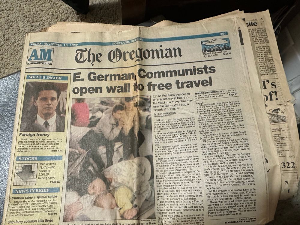 Photo of the Oregonian newspaper from November 10, 1989 with the headline “East German Communists open wall to free travel” with a story about the beginnings of the fall of the Berlin Wall. Photo shows East German refugees waiting in a shelter in the West. Also there is a story about Colin Firth’s new film, the stock market is down, and it was 50° and rainy.