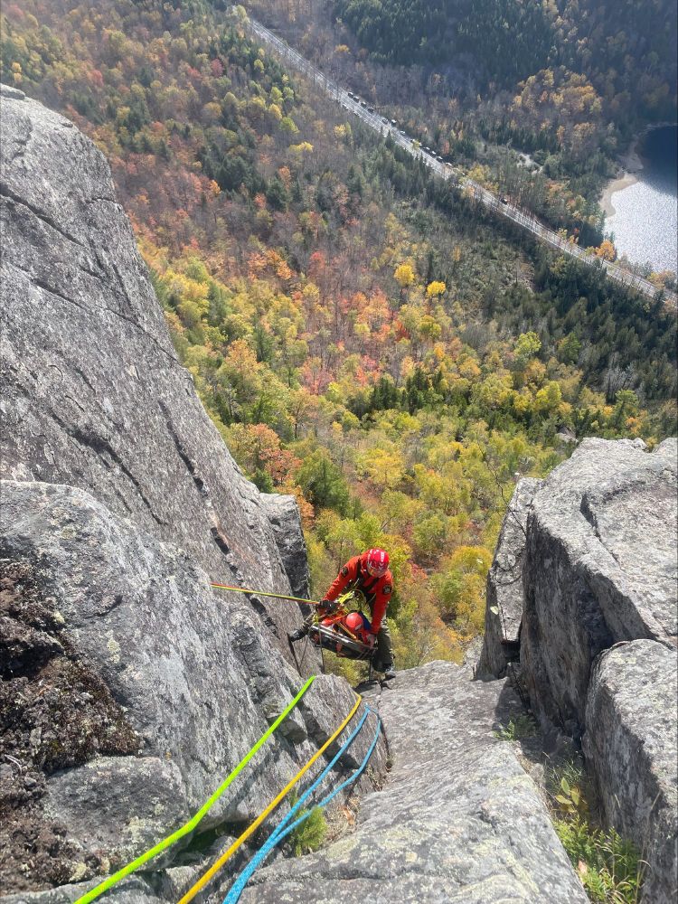 A person wearing a helmet while repelling on a steep cliff.
