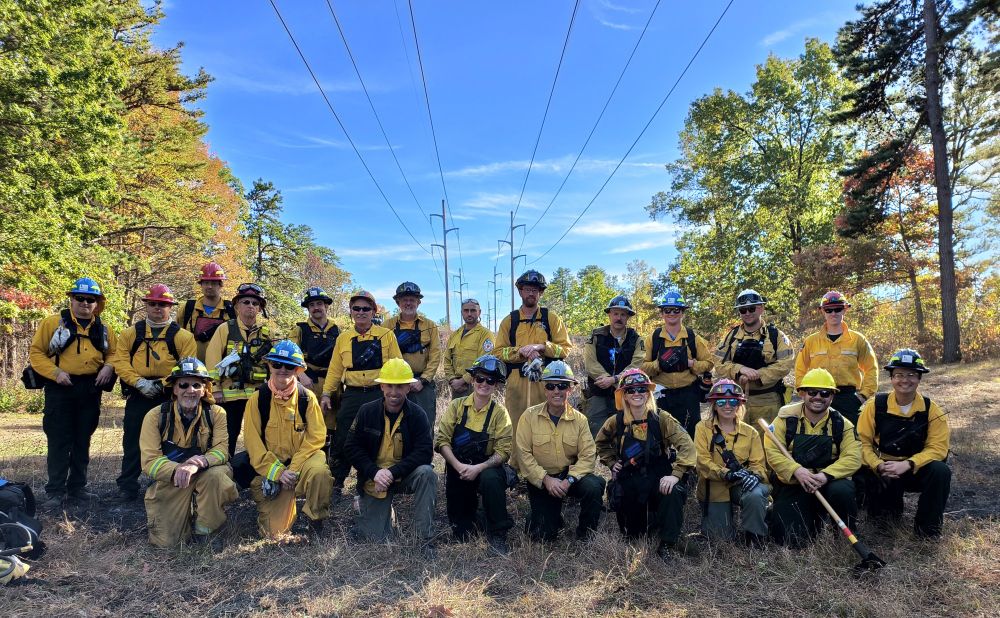 A group photo of people wearing firefighting gear outside.