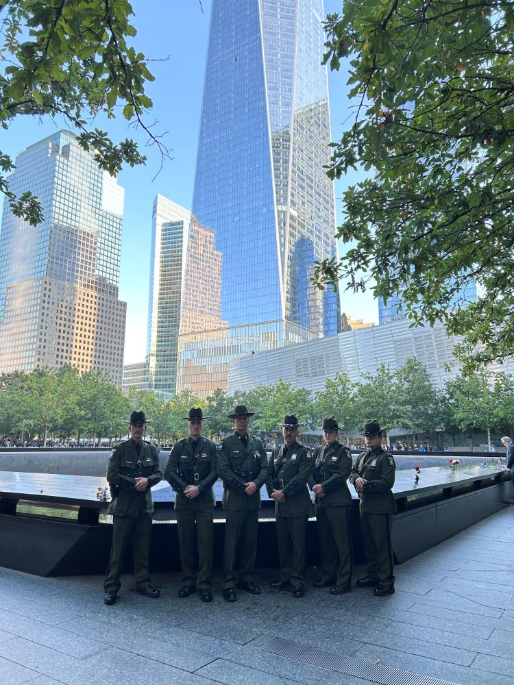 Five DEC Division of Law Enforcement Officers stand in front of the reflecting pool at the World Trade Center Memorial.