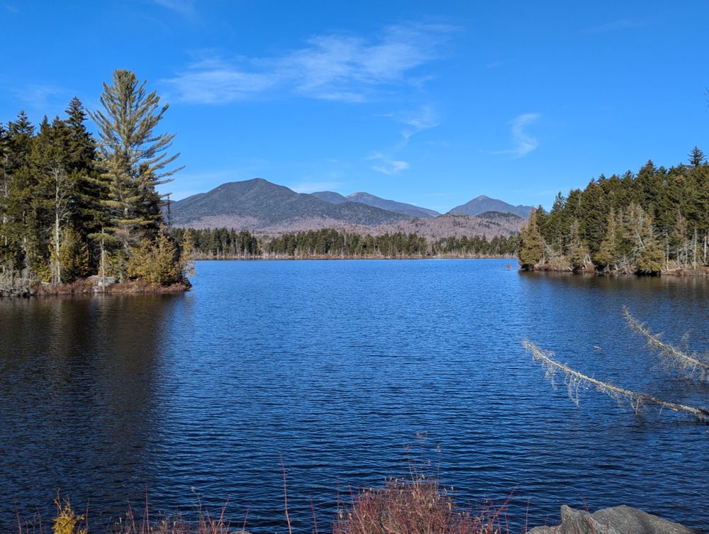 View from shore of water with mountains in background, clear blue skies.