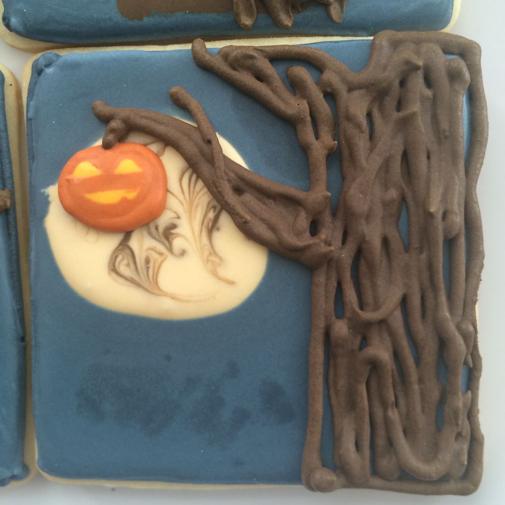 Another brown tree over a swirling blue background and a jack-o-lantern is hanging from a branch in front of a stylized moon in the background 
