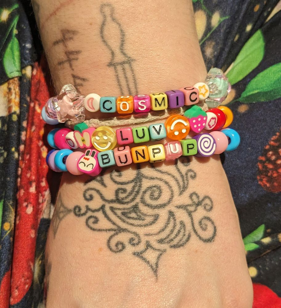 3 colorful candy bracelets which read "cosmic" , "luv", and "bunpup"