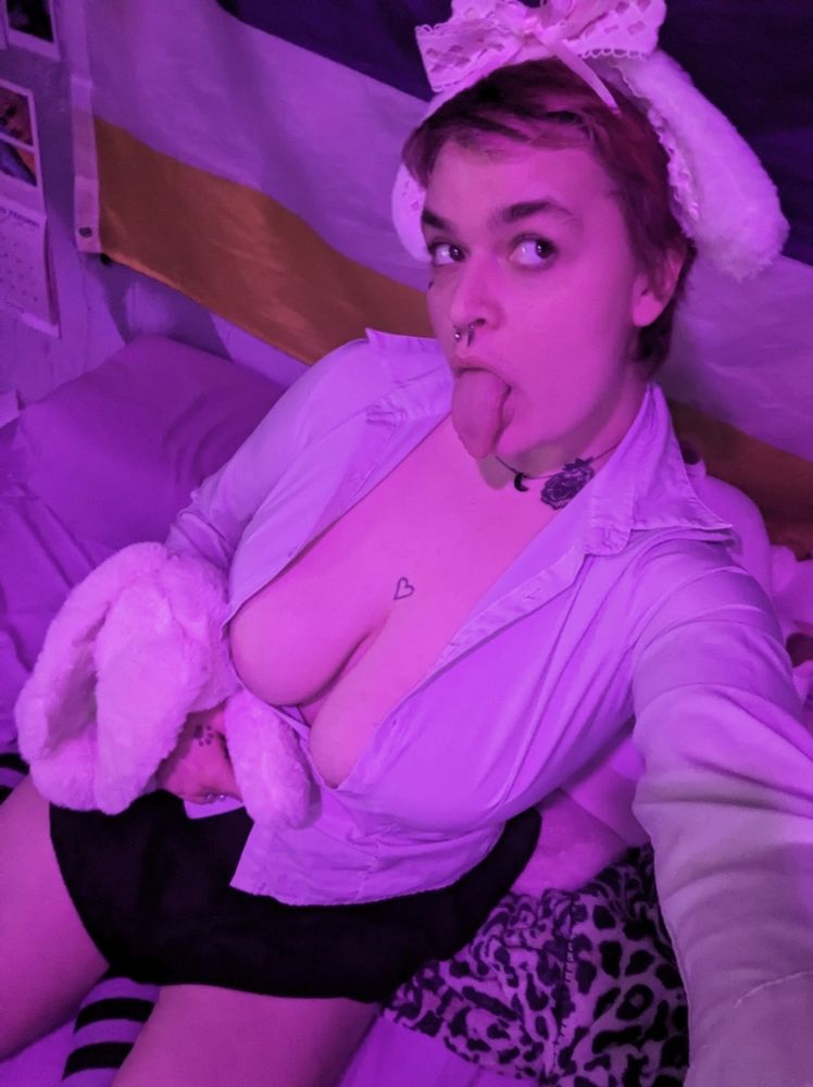 Nebula the bunny puppy with white ears and a pink bow in a white button up with a lot of cleavage and a short black skirt, holding a white bunny plush named Annalise, all in purple lighting