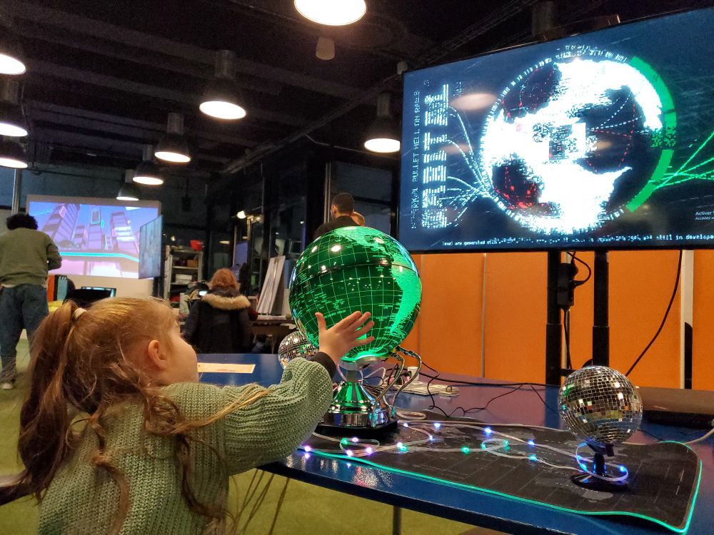 A cute little girl trying to rotate the globe but she's too small and too young to win the game.