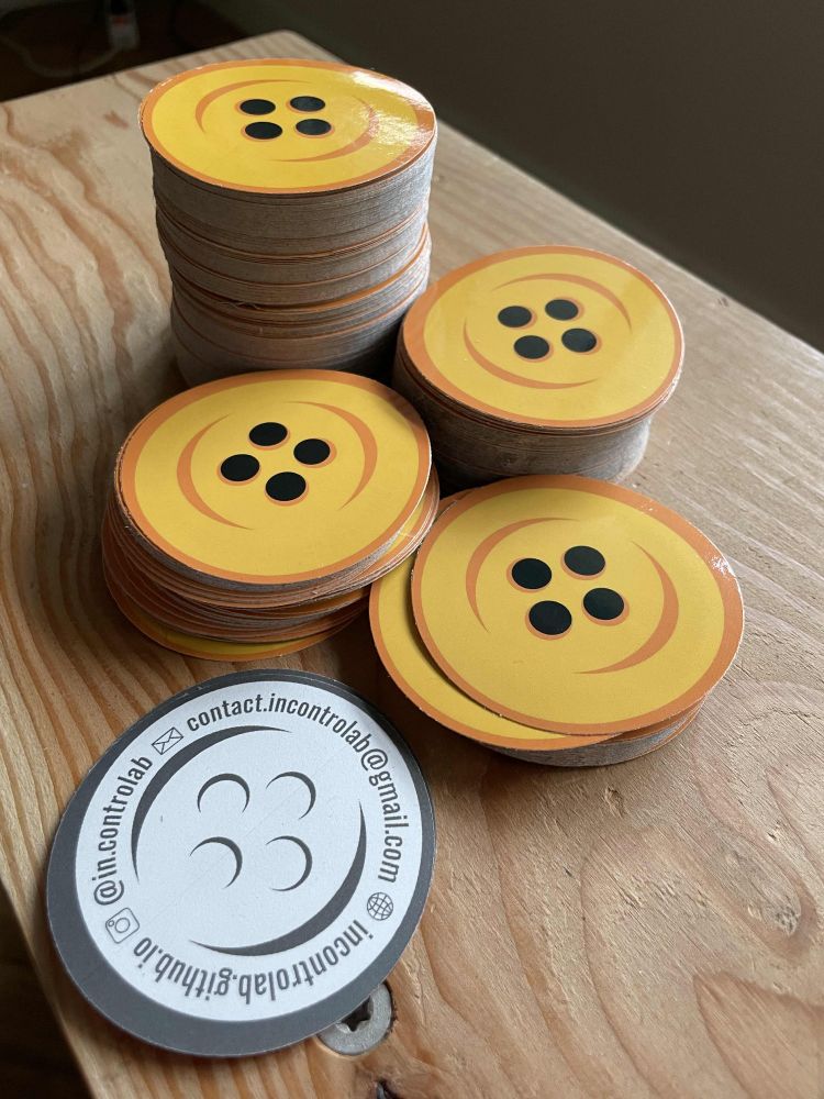 A few stacks of rounded stickers with a yellow button print on it : it's the logo of the incontrolab collective