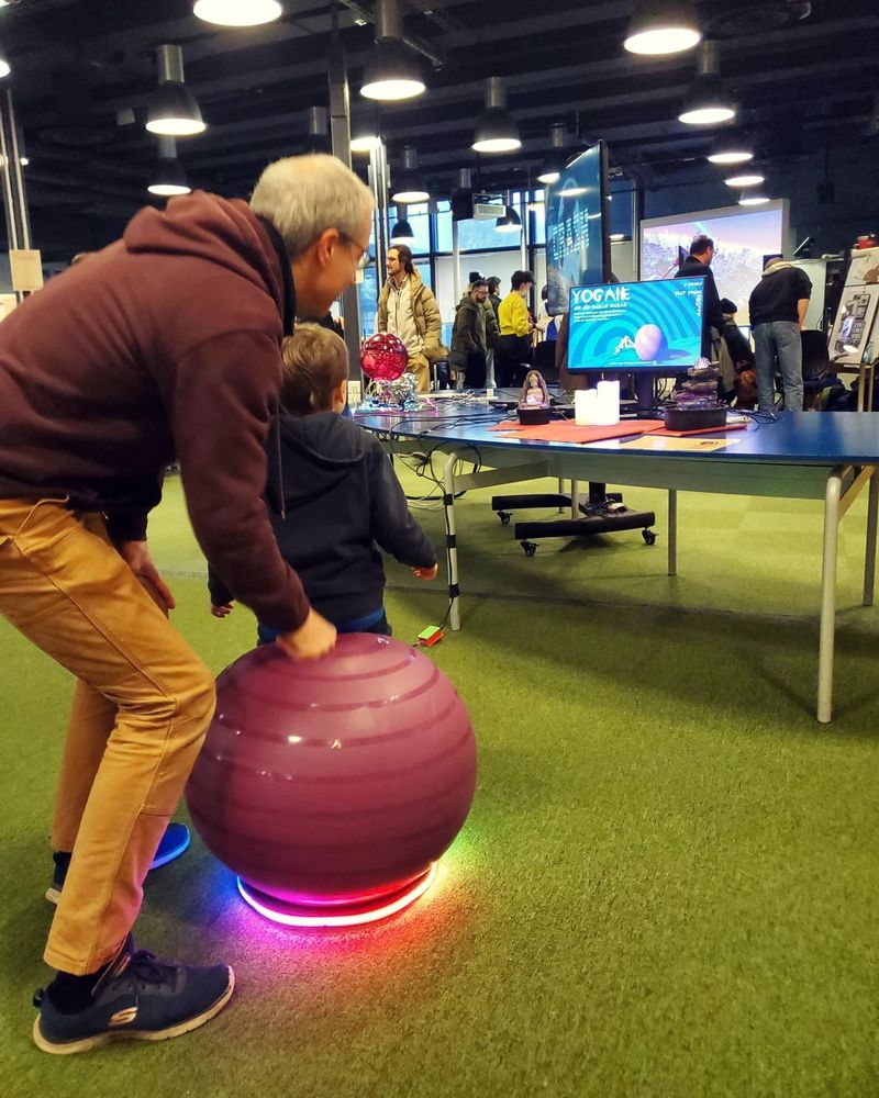 A father helping his kid to sit on the yoga ball.