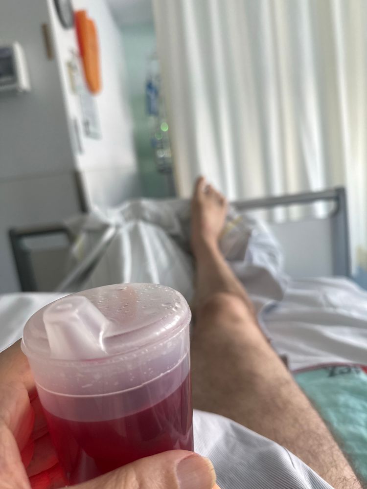 Ein Männerbein und ein schnabelbecher mit rotem Inhalt